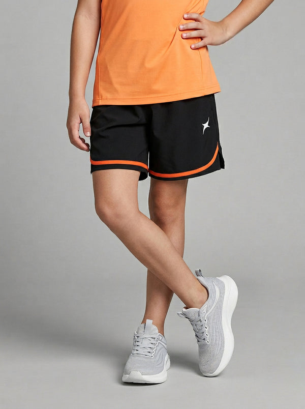 A child wearing black shorts with orange trim and an orange top on a gray background