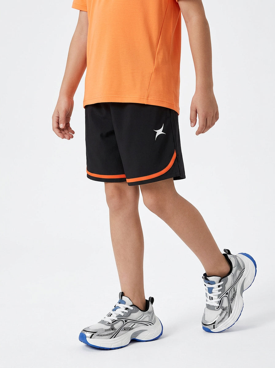 A boy wearing an orange T-shirt, black shorts on a white background