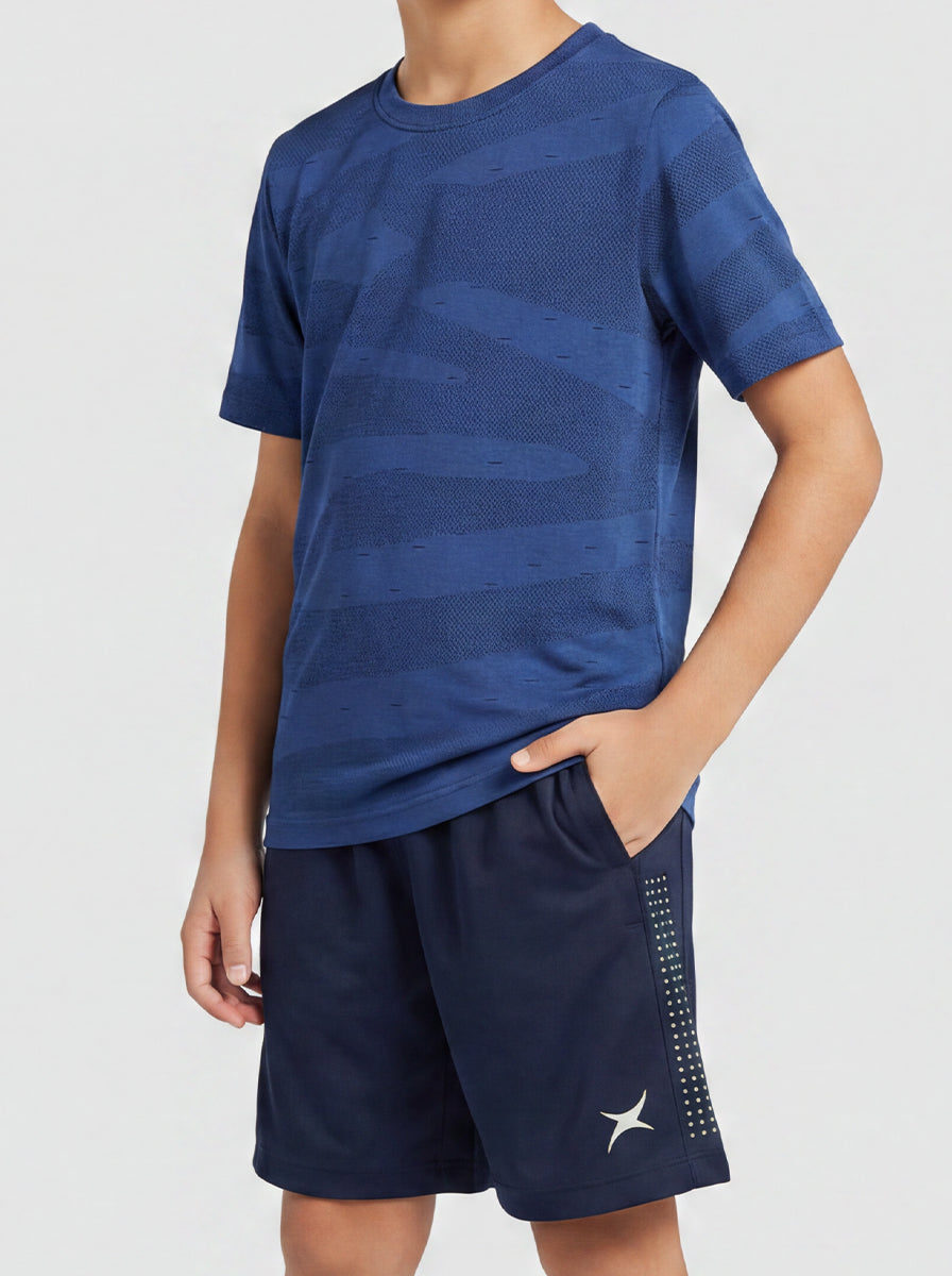 A boy wearing a blue sports outfit with a white logo on a light gray background