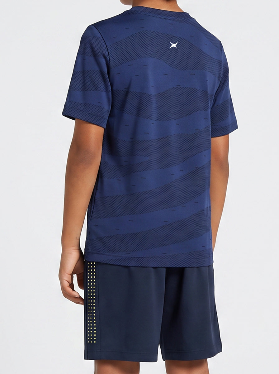 A boy wearing a blue sports outfit with a logo on the back against a white background