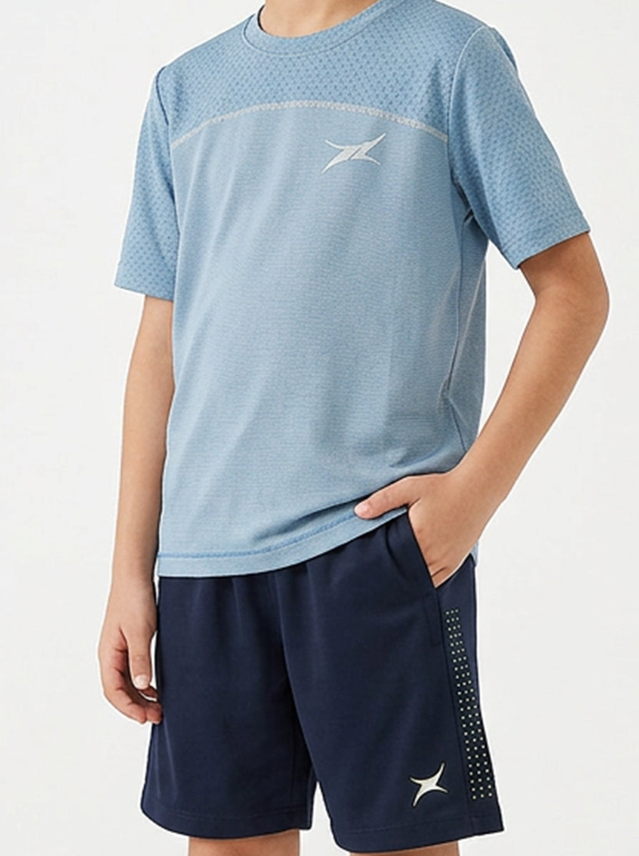A boy wearing a blue sports T-shirt and navy shorts with a brand logo on a white background