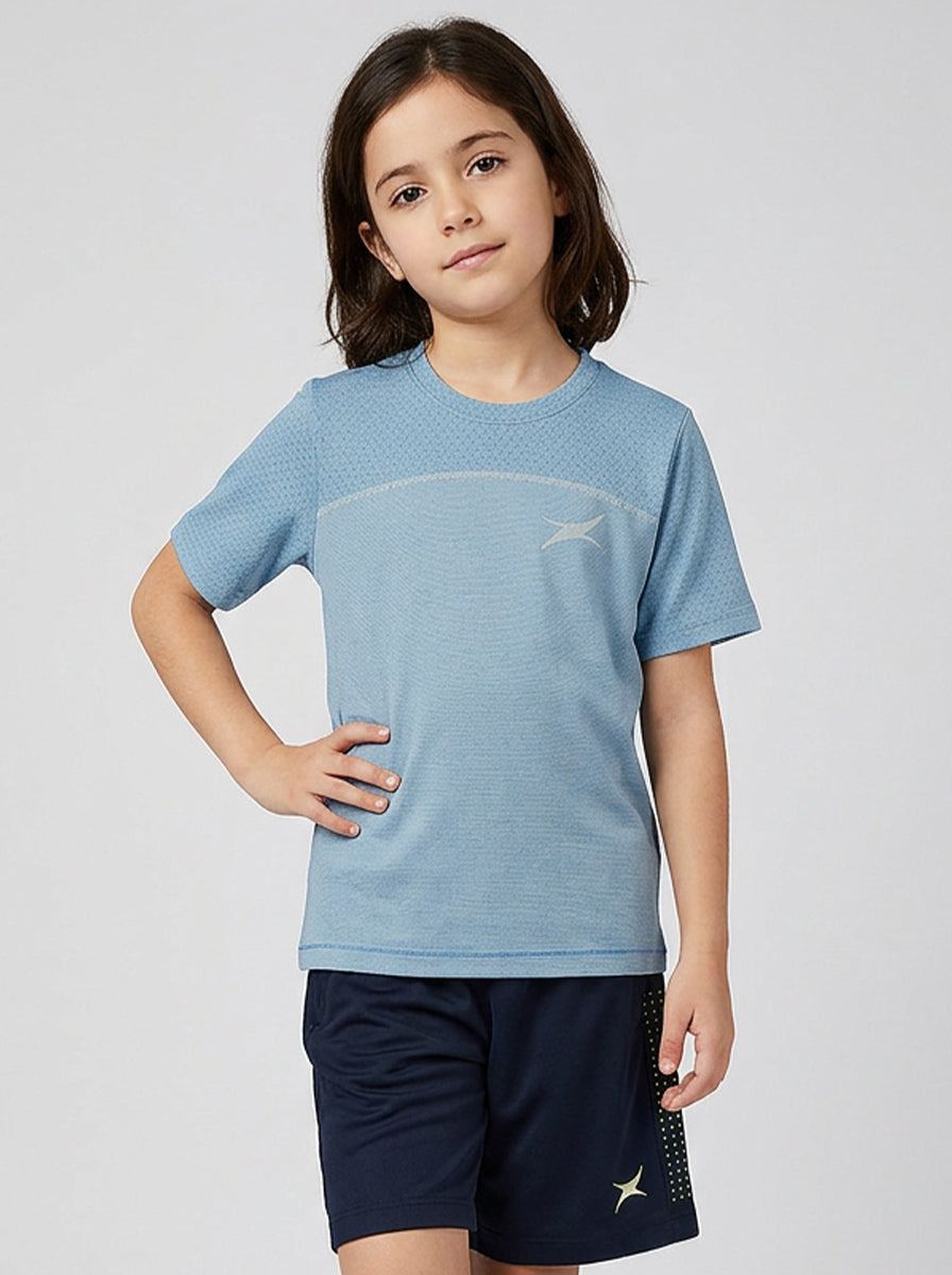 Child wearing a blue sports shirt and navy shorts on a light gray background