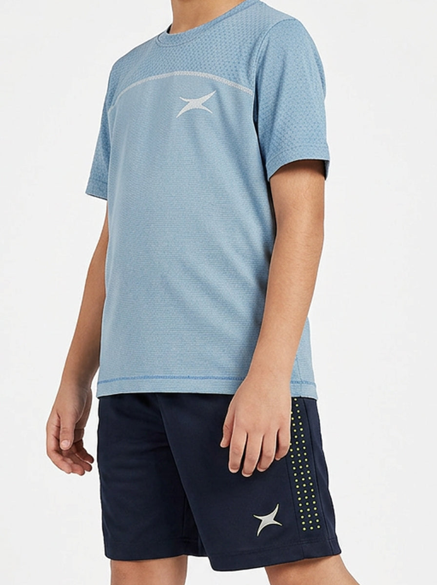 A boy wearing a blue athletic shirt and navy shorts with a brand logo on a white background