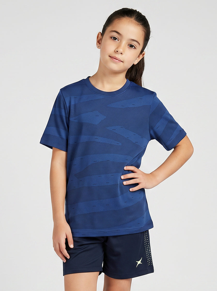 A girl wearing a blue sports t-shirt and shorts on a light gray background