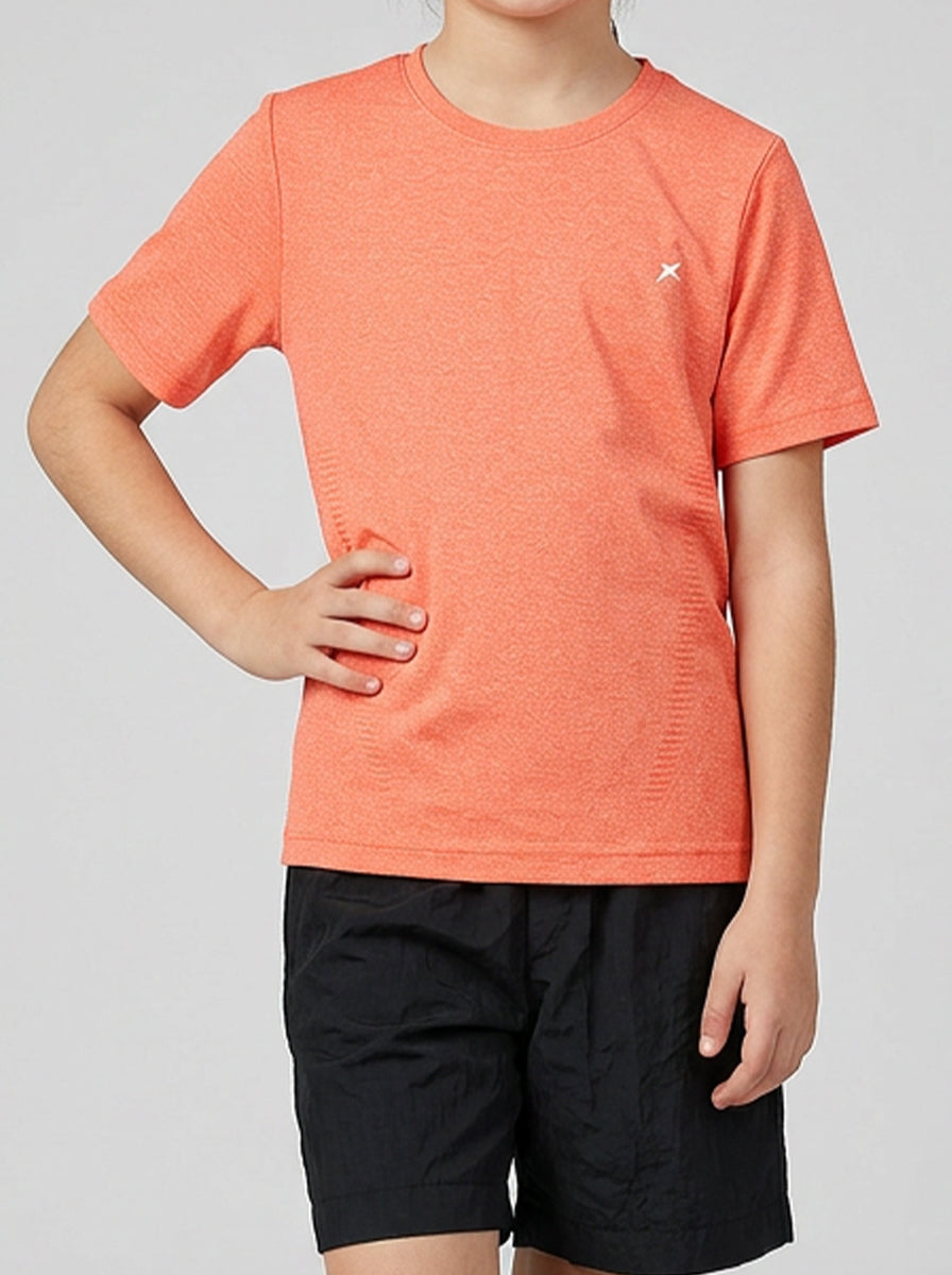 Child wearing an orange sports t-shirt and black shorts on a gray background
