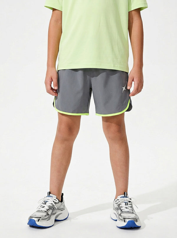 A boy wearing gray shorts with neon green trim on a white background