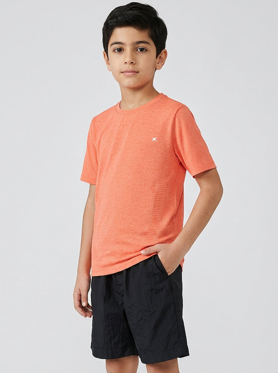 Child wearing an orange t-shirt and black shorts on a white background