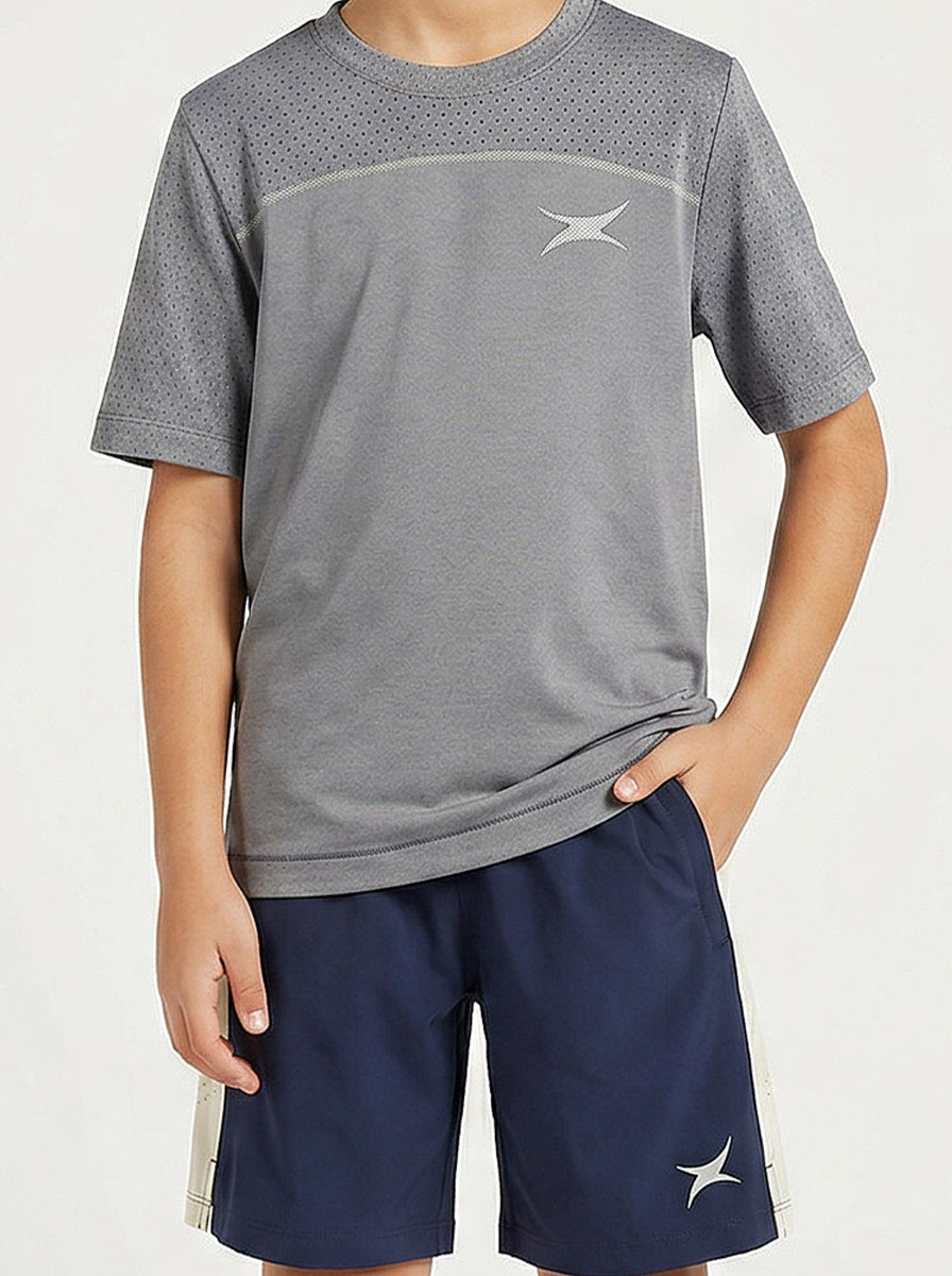Child wearing a gray sports t-shirt and navy shorts with a brand logo on a light background
