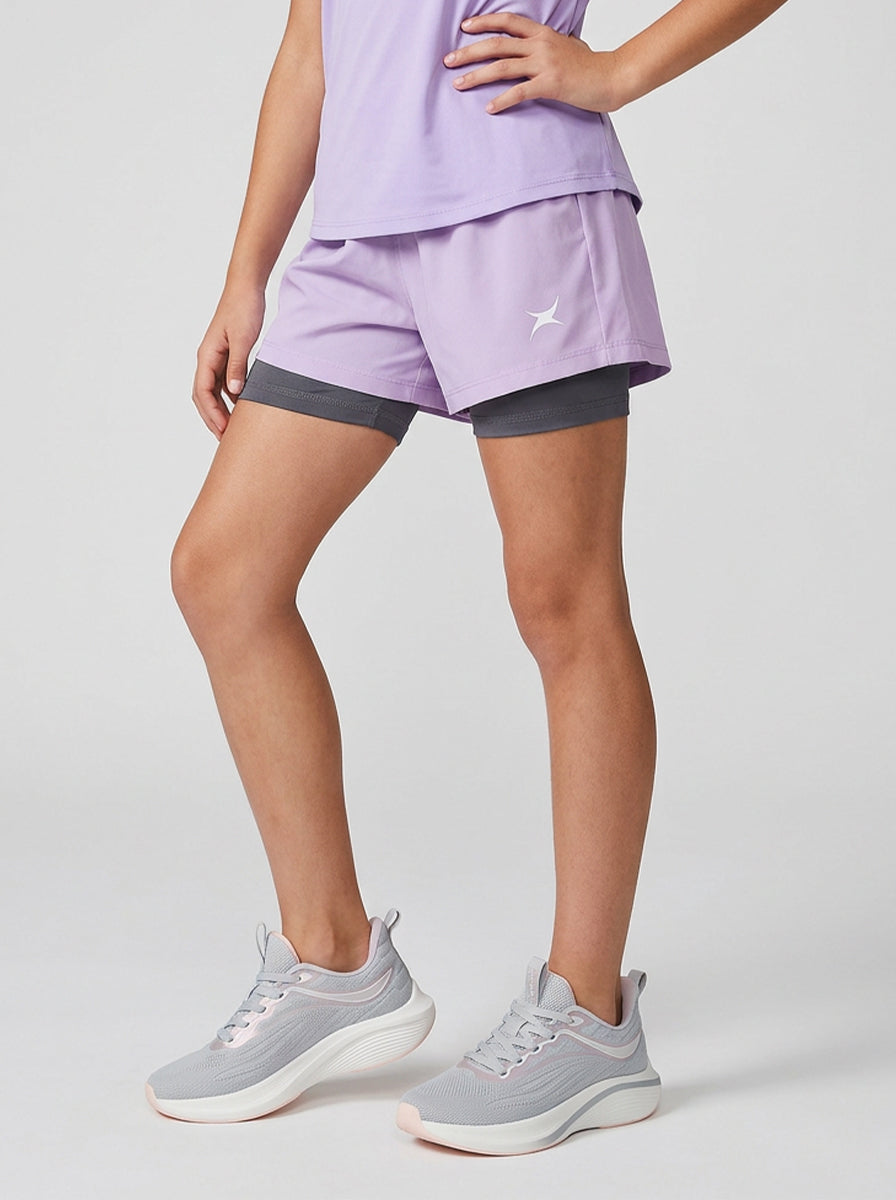 A girl wearing a two-tone sports outfit with gray and purple shorts on a light gray background