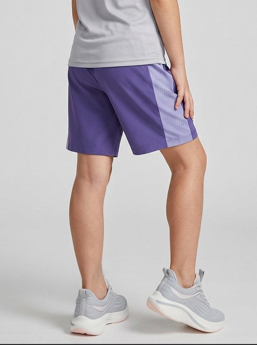 A girl wearing lilac shorts with a logo on a light gray background
