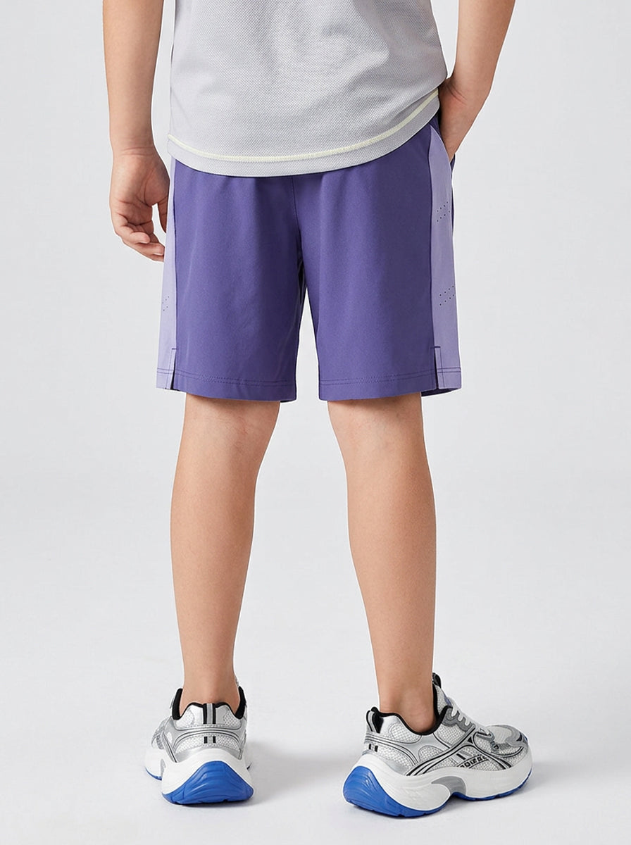 A boy wearing purple shorts with a white logo on a light gray background
