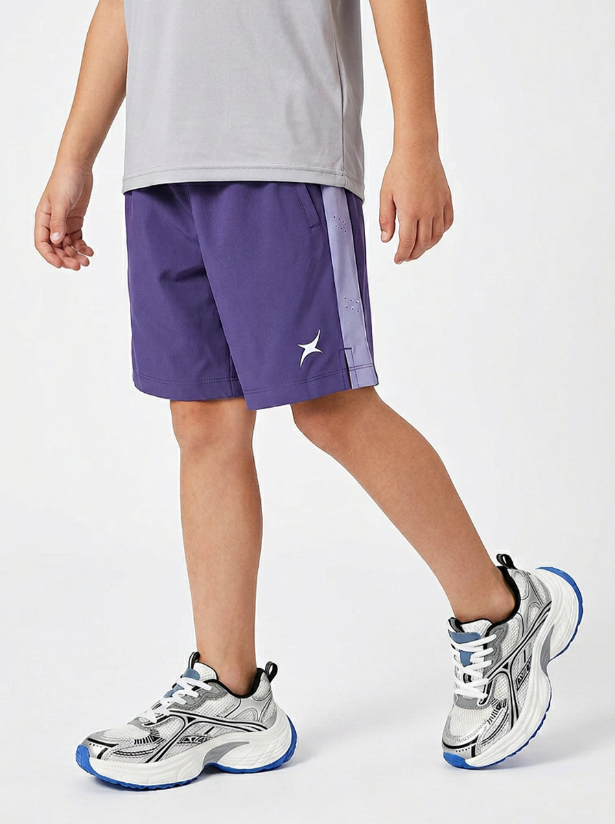 A boy wearing purple shorts with a white logo on a light gray background