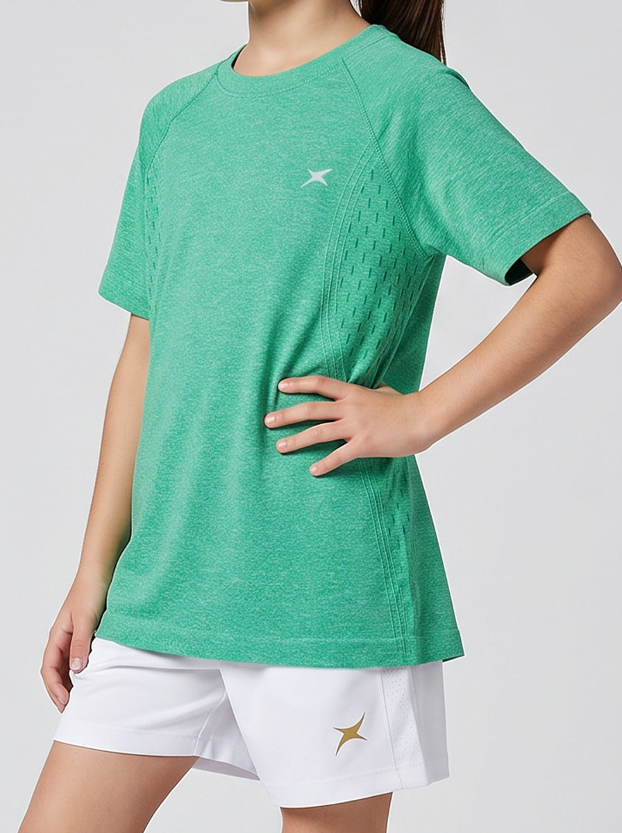 A girl wearing a green sports t-shirt and white shorts with a logo on a plain background