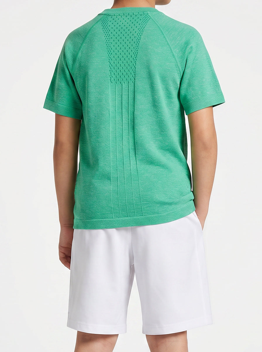 A boy wearing a green t-shirt and white shorts on a plain background