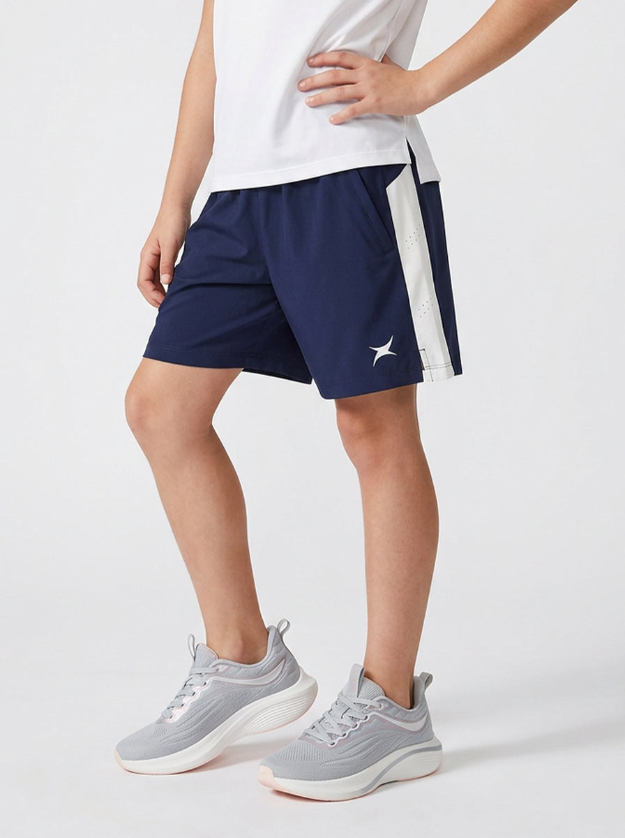 A child wearing navy shorts with a logo on a light gray background