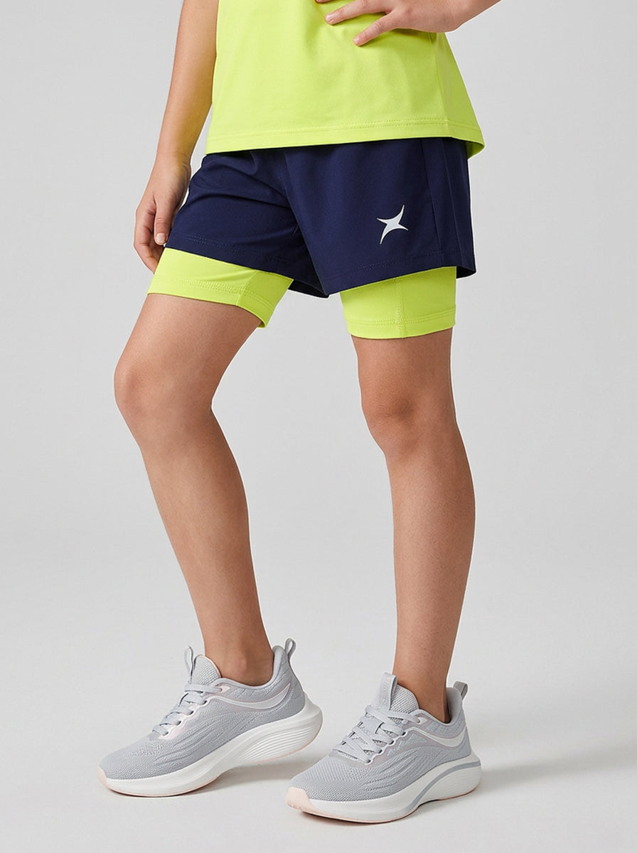 A girl wearing navy and green sports shorts on a gray background