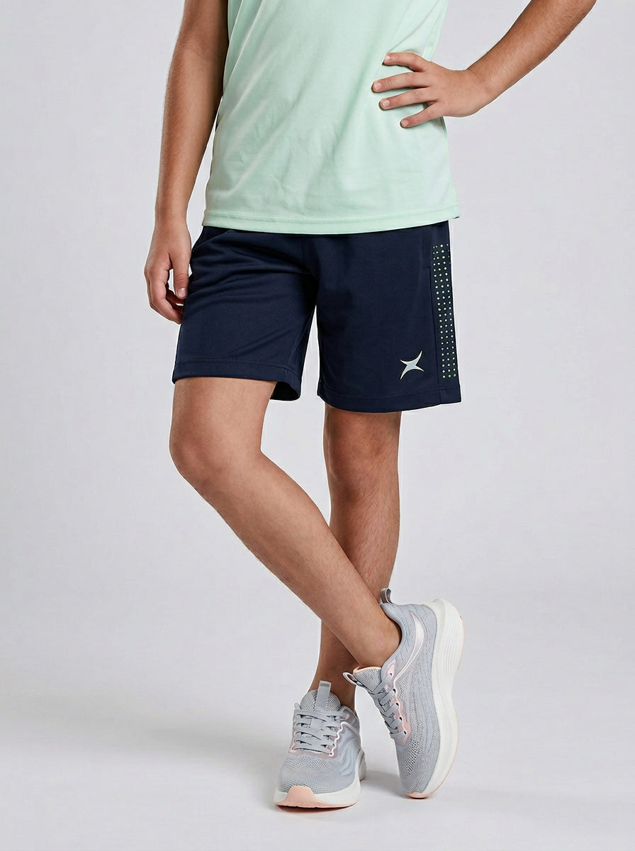 A child wearing navy sports shorts with a brand logo on a light gray background