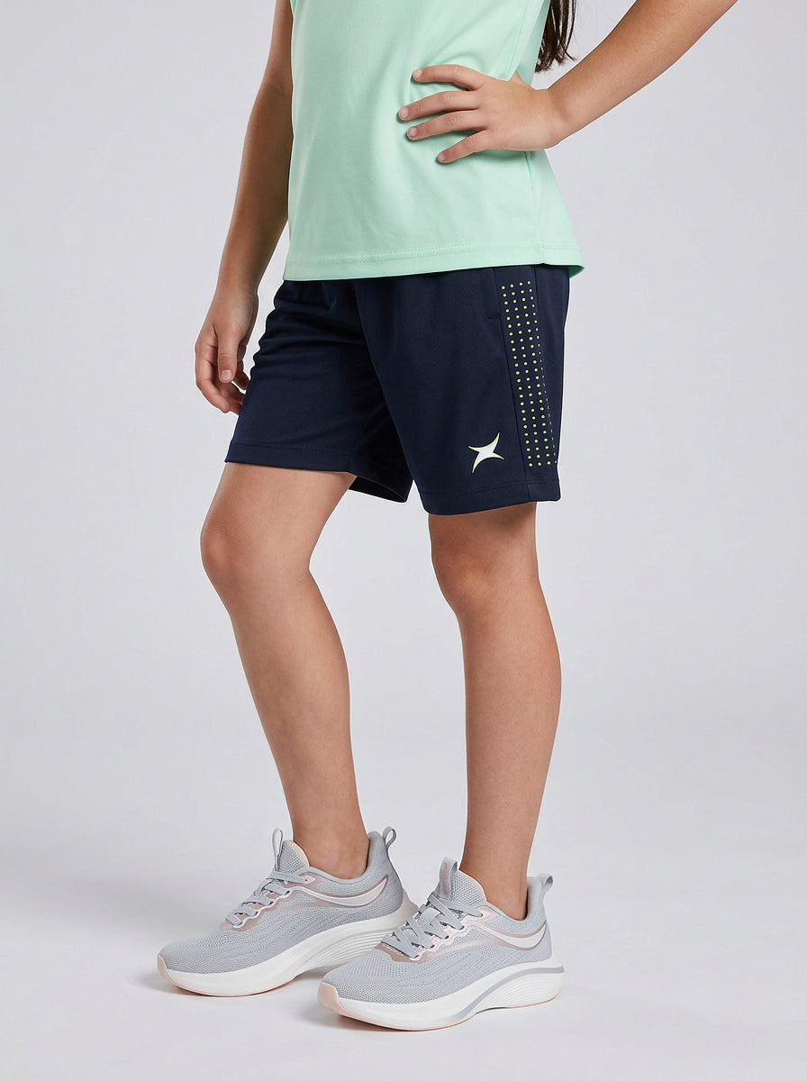 A boy wearing navy shorts with a star design on a light gray background