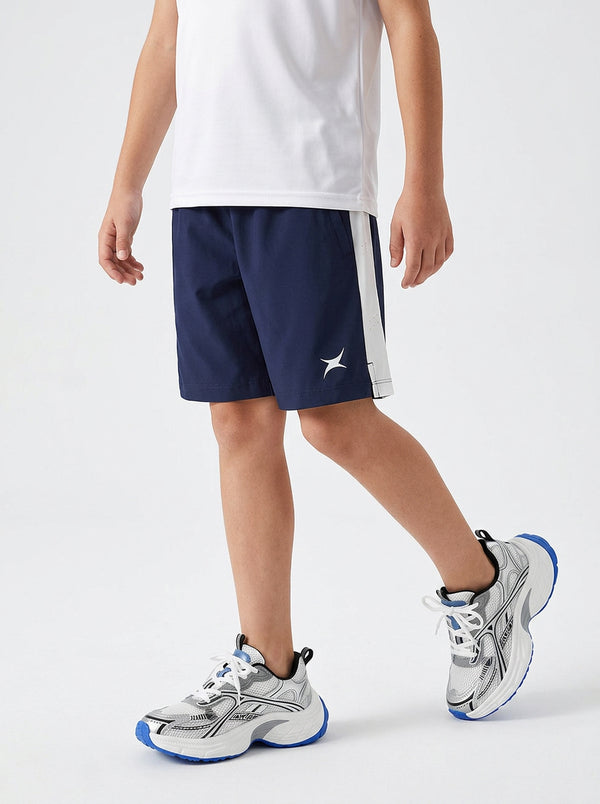 A boy wearing navy shorts with a white logo on a light gray background
