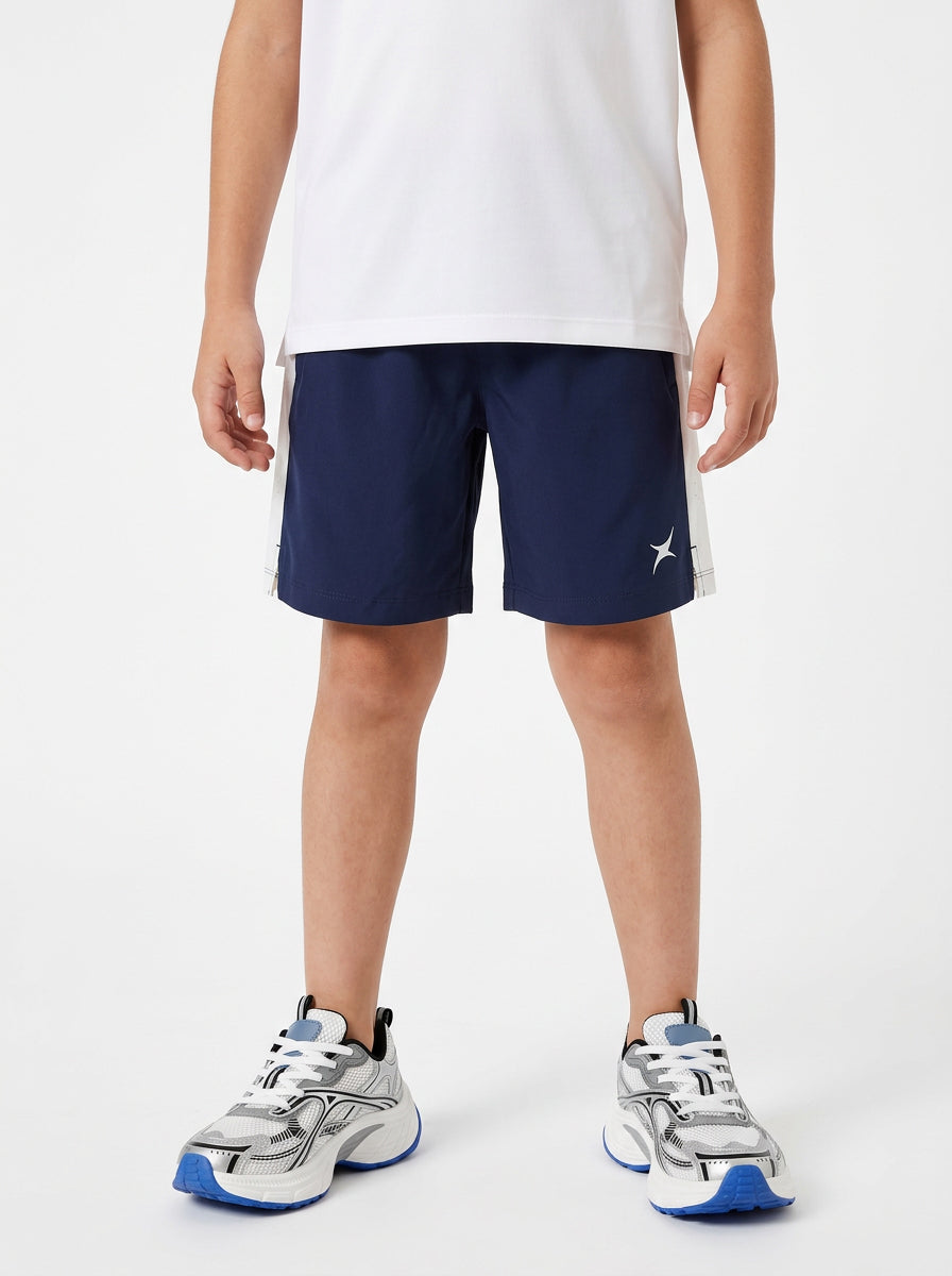A boy wearing navy shorts with a white logo on a white background