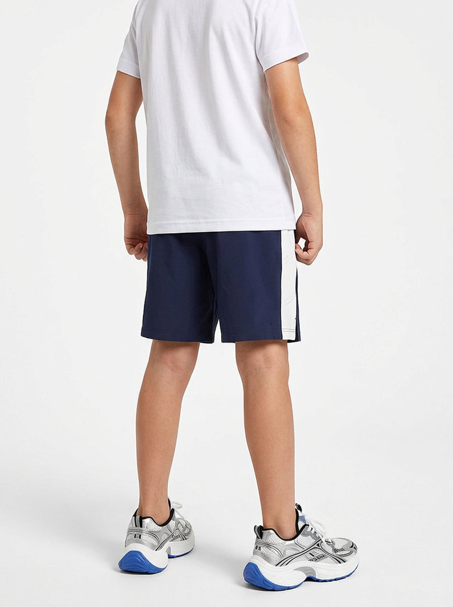 A boy wearing navy shorts with a white logo on a white background
