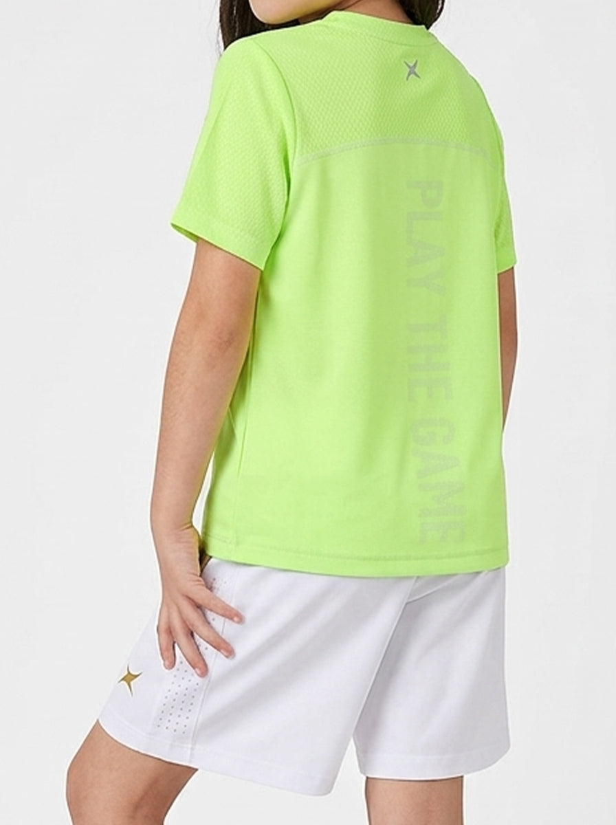 A girl wearing a bright green t-shirt with text and white shorts on a light gray background