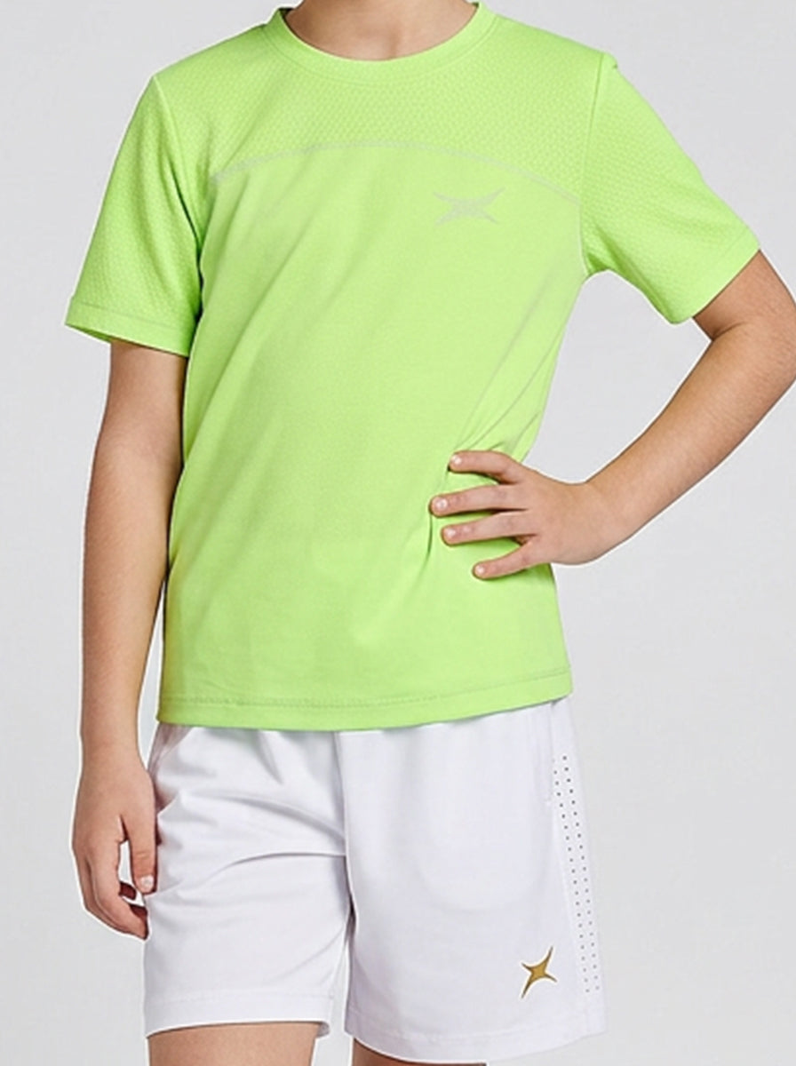 Child wearing a bright green t-shirt and white shorts on a plain background