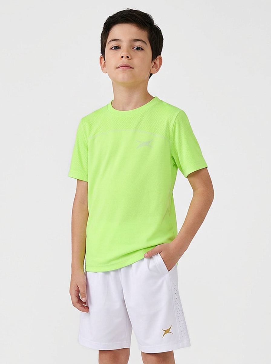 Child wearing a bright green sports t-shirt and white shorts on a light gray background