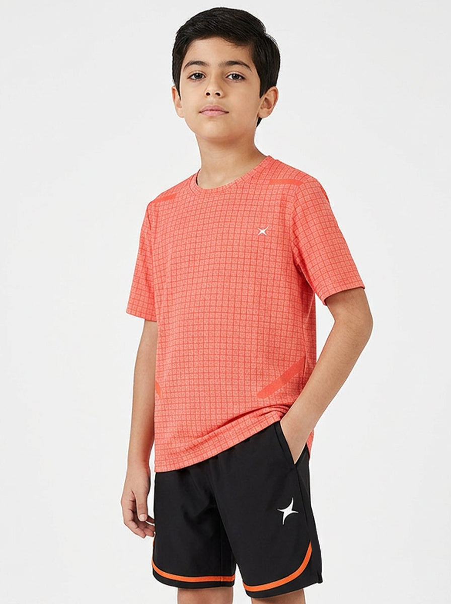 Child wearing an orange checkered sports t-shirt and black shorts with orange trim on a white background