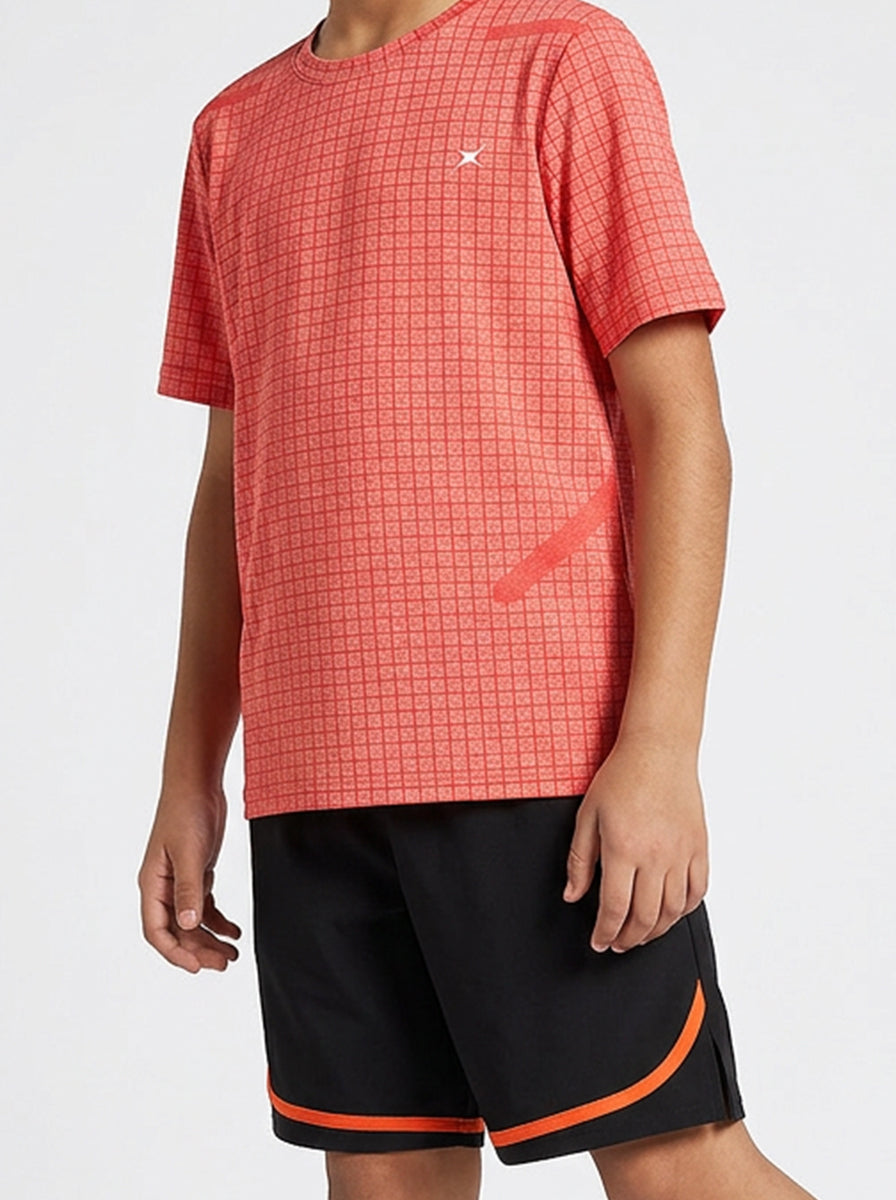 Child wearing an orange checkered sports t-shirt and black shorts with orange trim on a white background