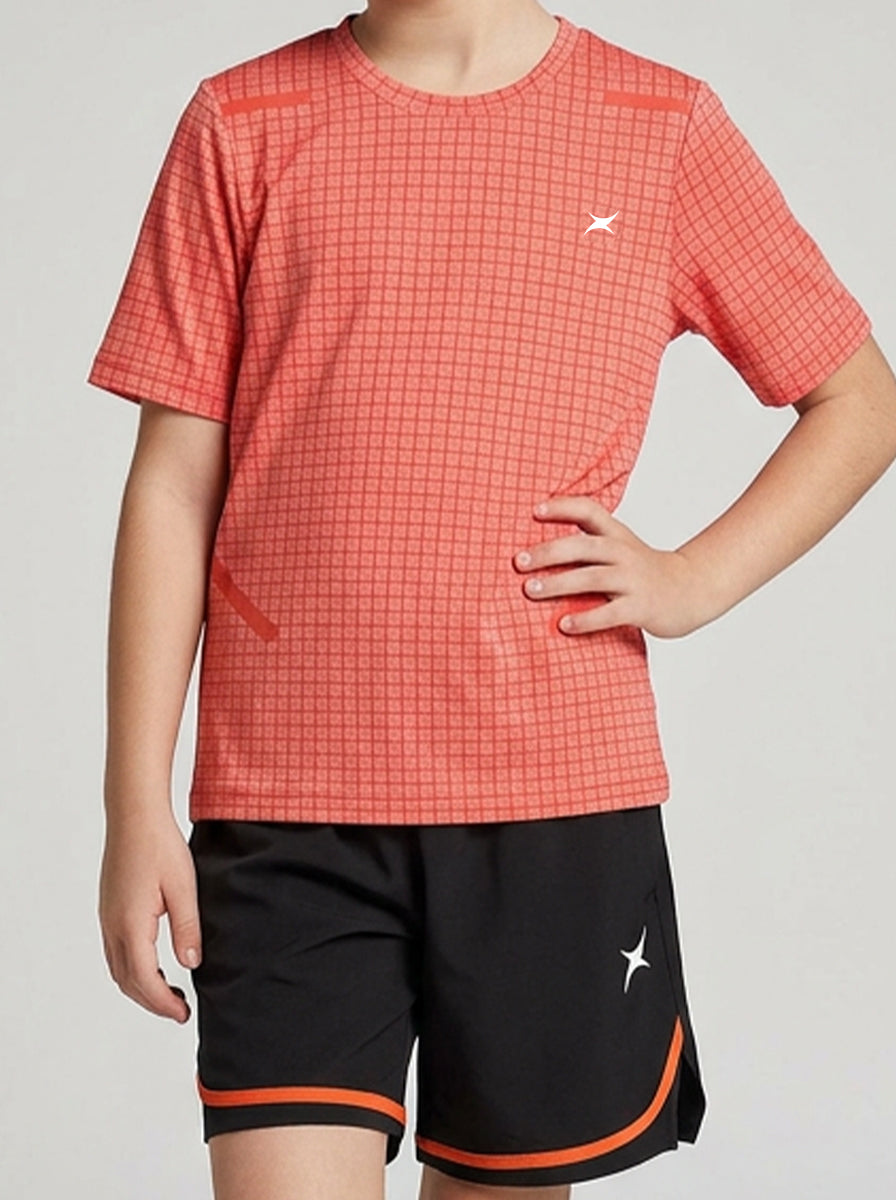 A girl wearing an orange checkered sports t-shirt and black shorts with orange accents on a plain background
