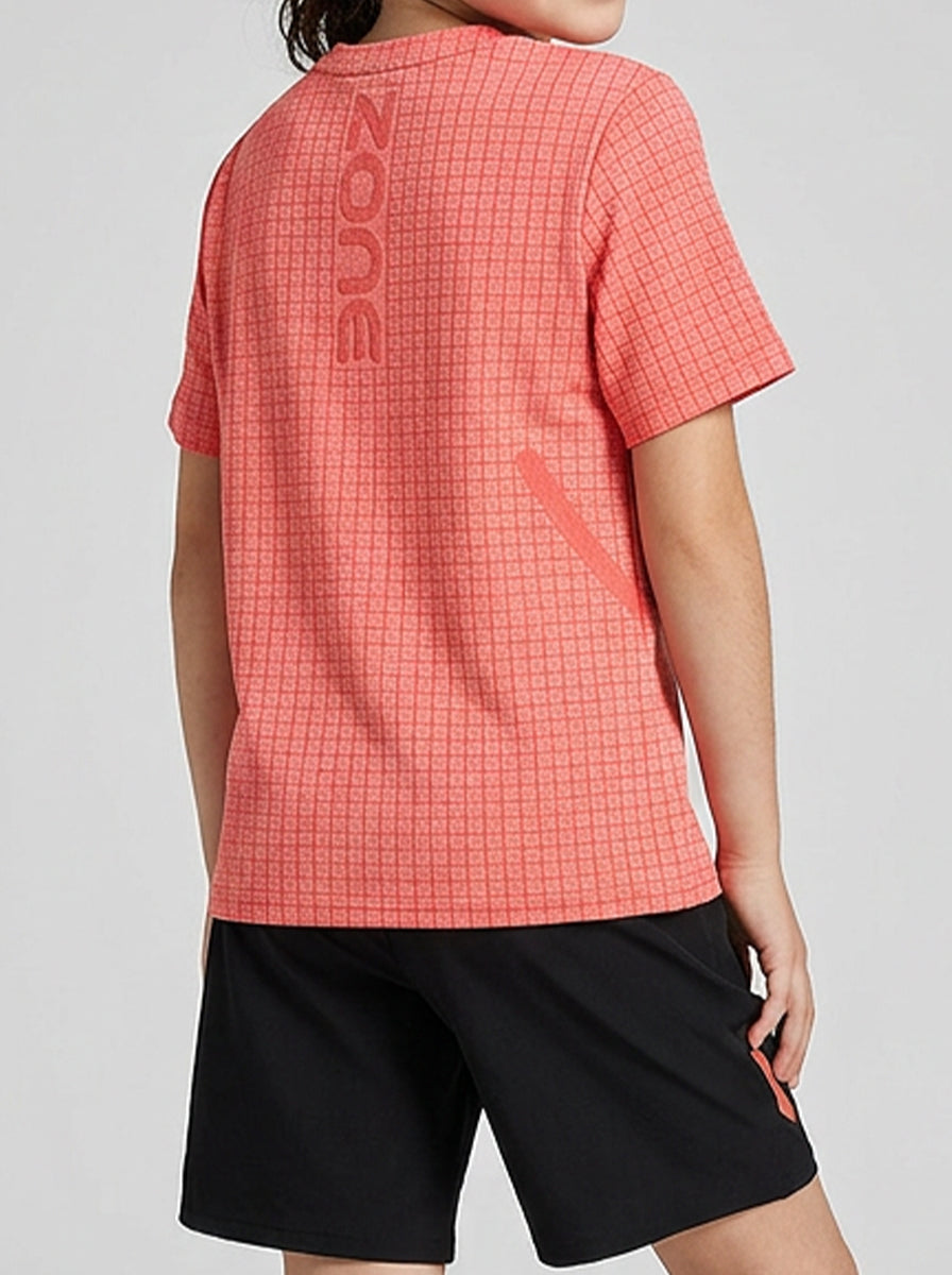 A girl wearing an orange checkered sports t-shirt with 'Zone' branding on the back, standing against a gray background.