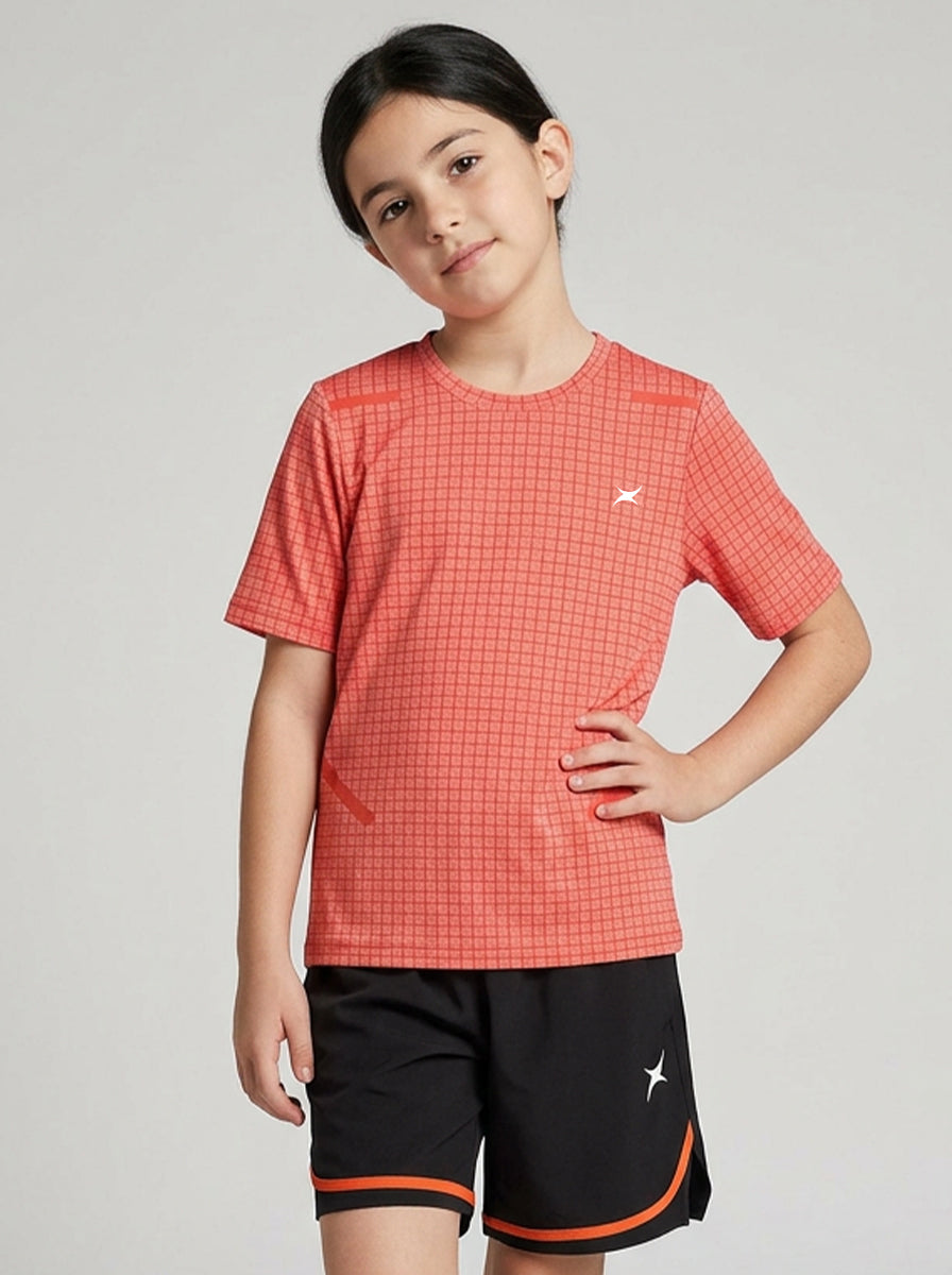 Child wearing an orange checkered sports t-shirt and black shorts with orange accents on a gray background