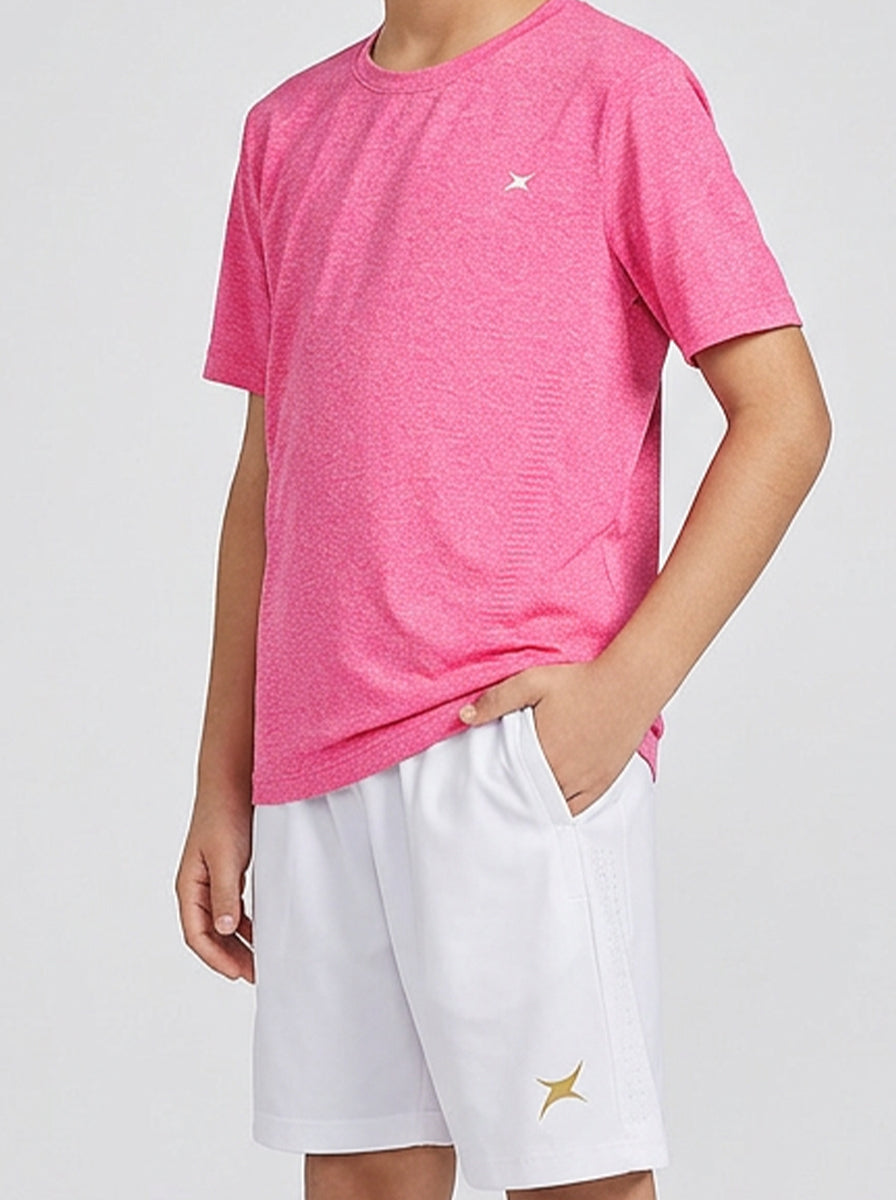 A boy wearing a pink t-shirt and white shorts with a brand logo on a light gray background