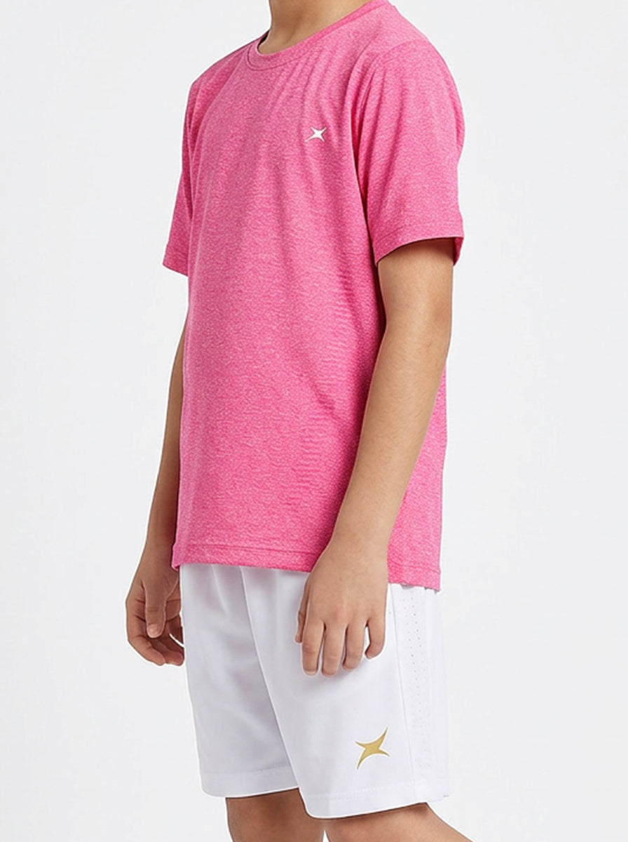 A boy wearing a pink t-shirt and white shorts on a light gray background