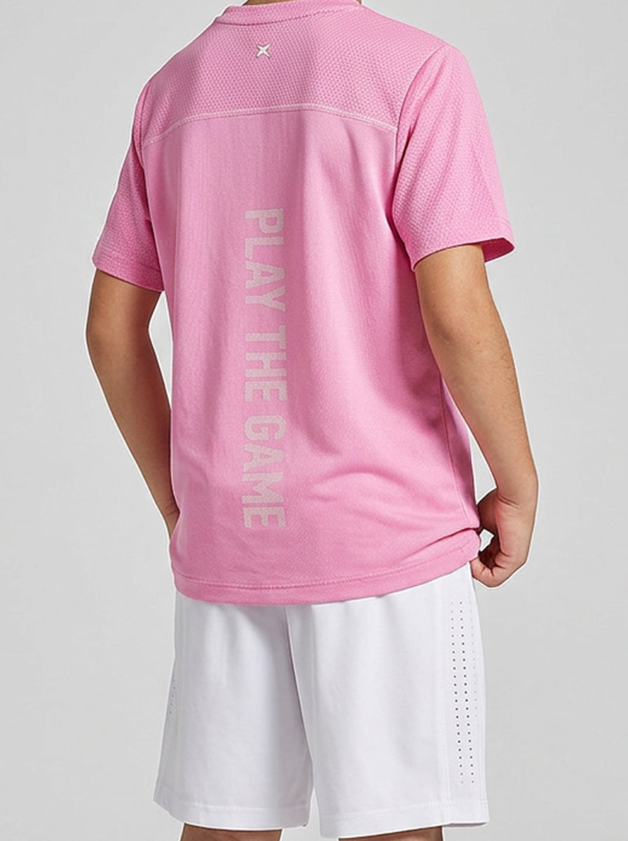 A boy wearing a pink sports jersey with 'Play The Game' text on the back, standing against a light gray background.
