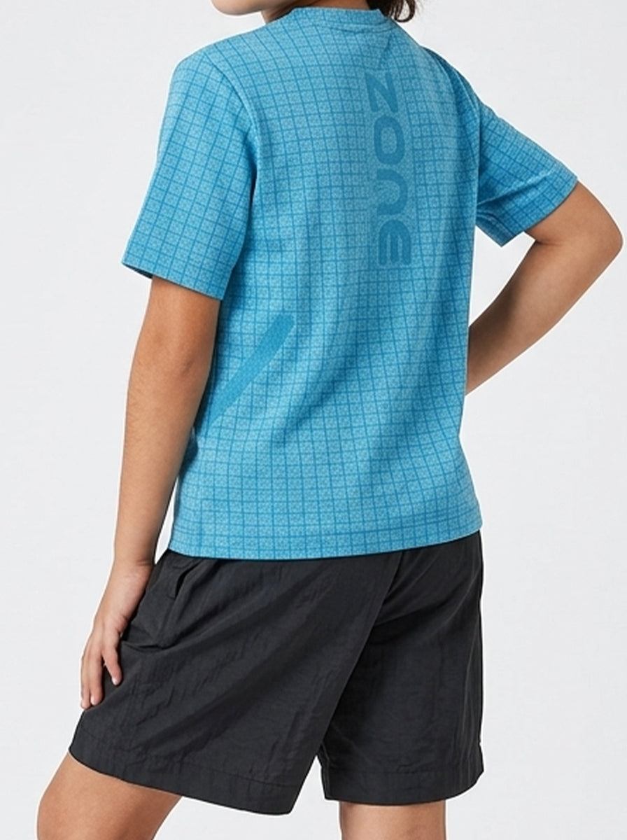 A girl wearing a blue checkered sports t-shirt and black shorts on a white background