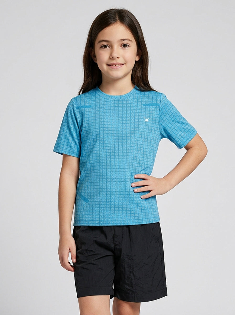 Child wearing a blue checkered sports t-shirt and black shorts on a light gray background