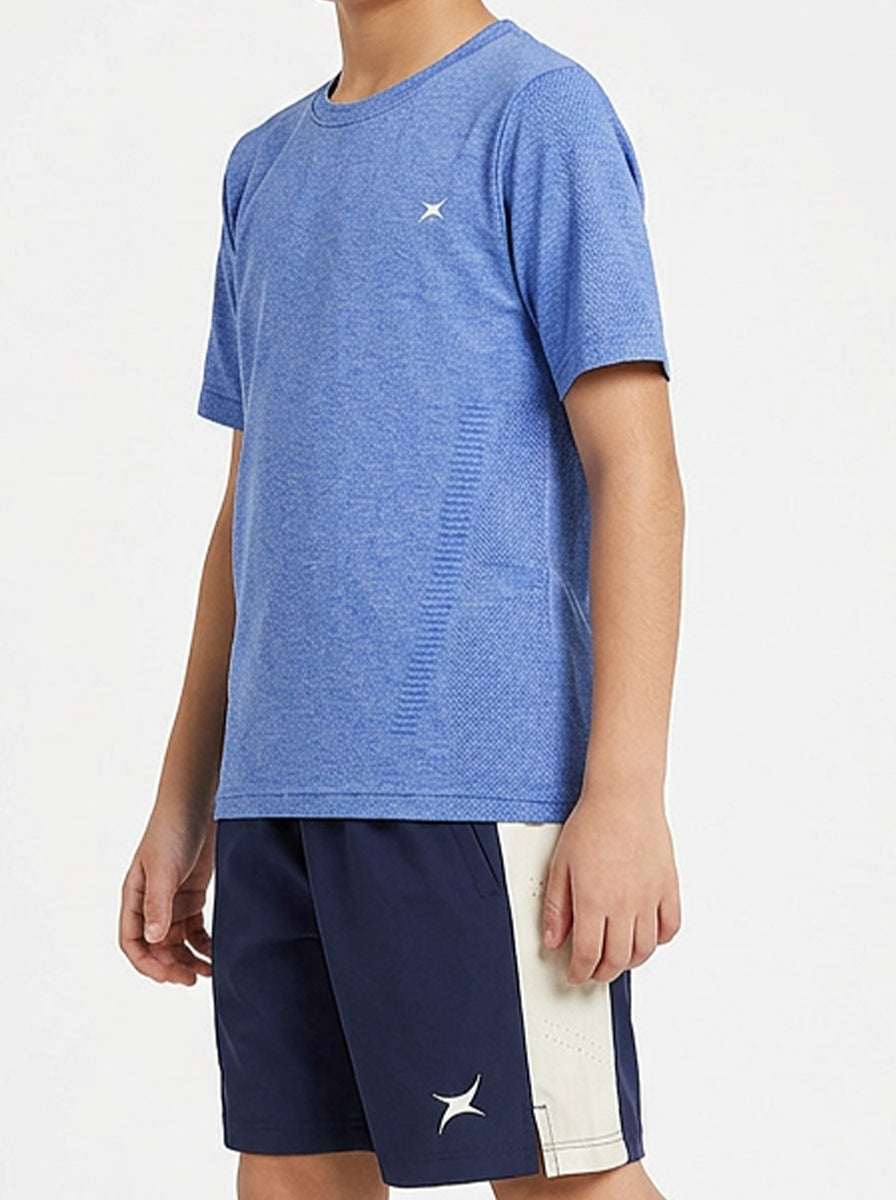 A boy wearing a blue sports t-shirt and navy shorts with a white stripe on a light gray background
