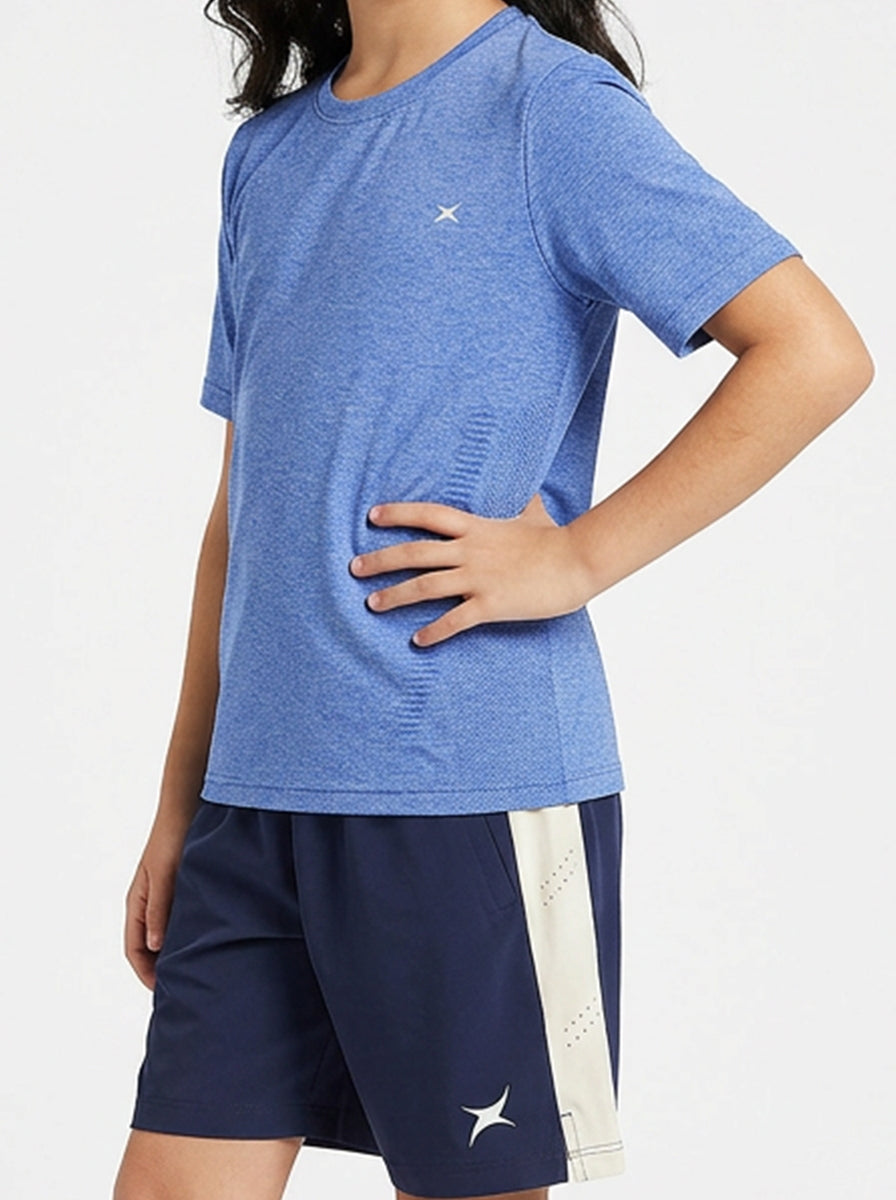 A girl wearing a blue sports shirt and navy shorts with a white stripe on a light gray background