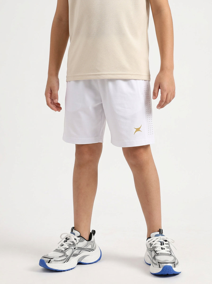 A boy wearing white shorts on a light gray background